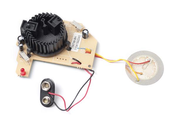 component parts of a domestic smoke detector showing the sensor chamber with lid removed, battery connector below and piezo sounder to the right