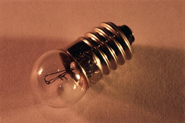 Small spherical torch lamp with a screw mount lying at an angle with the globe facing the camera on brown with copyspace