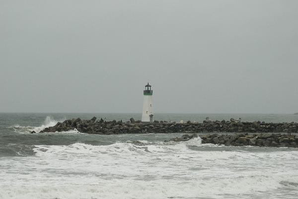 concrete breakwaters deflect pacific ocean waves, marked by a navigation light at the entrance to santa cruz marina