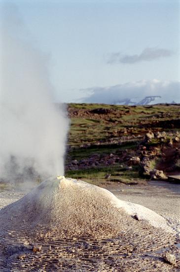 Steam ejecting from the top of a mound around the mouth of a geyser, a natural hot spring that releases pressure by releasing a column of water and steam