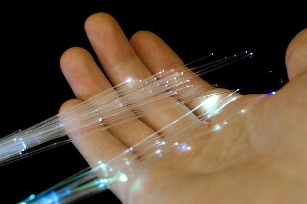 Fibre optics displayed on a male hand with long thin flexible extruded glass filaments acting as a wave guide in transmitting light and information