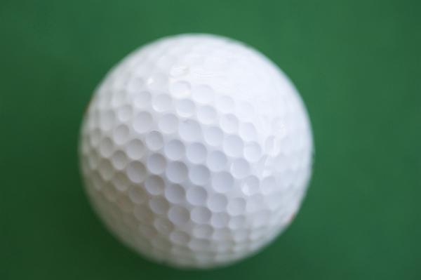 Close-up of a white golf ball, with dimple pattern, the dimples on the ball are designed to improve the balls aerodynamics when flying through the air at speed