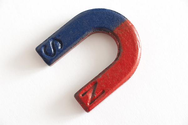 Horseshoe permanent magnet with red and blue positive and negative poles to create a magnetic field lying on a white background