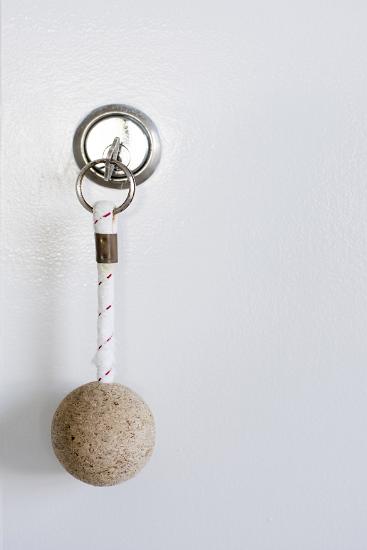 Small key with attached round float on a short cord in a lock in a close up with copy space. The cork is less dense than water and allows the denser key to float if dropped into the ocean