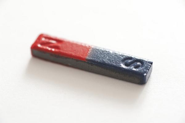 Scientific bar magnet with a red and blue positive and negative pole for attracting metallic objects such as iron or for creating a magnetic field, pictured on a white background