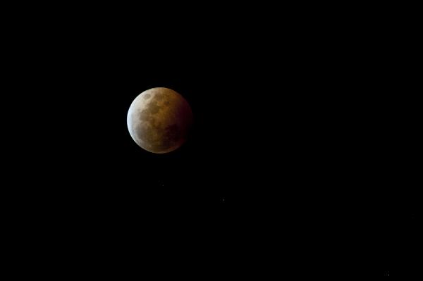 Partially eclipsed moon in a dark sky during a lunar eclipse cause by alignment with the earths shadow