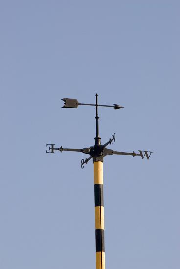 Weather vane with an arrow showing the wind direction and the four points of the compass below against a clear blue sky, this vane was located at the top of an observatory after 1pm when the time ball had fallen to the bottom of the mast