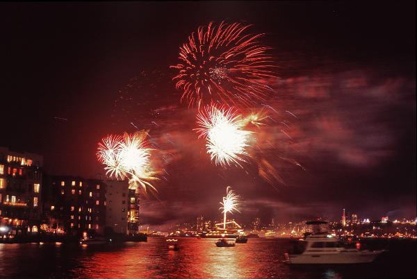 Red Fireworks Display Over City at night. The colours in fireworks are created using various chemicals, for example orange colours are generated through burning calcium, yellow sodium, blue copper, gold yellow colour from charcoal or iron