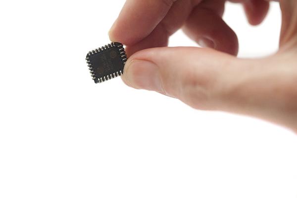Hand Holding Microchip with fingertips up close. this chip was used to stop computer code known as firmware