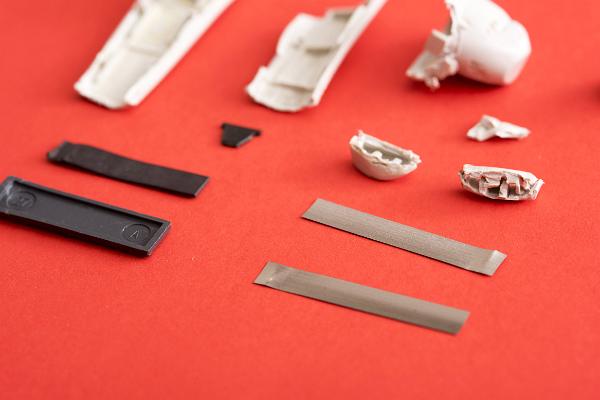Disassembled parts of a security tag lying on a red background with foreground copy space