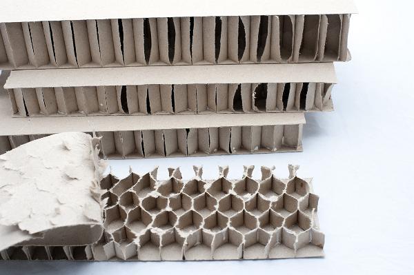 View with the outer layer of a reinforced cardboard panel peeled back to expose the honeycomb structural pattern for strength of the inner layer