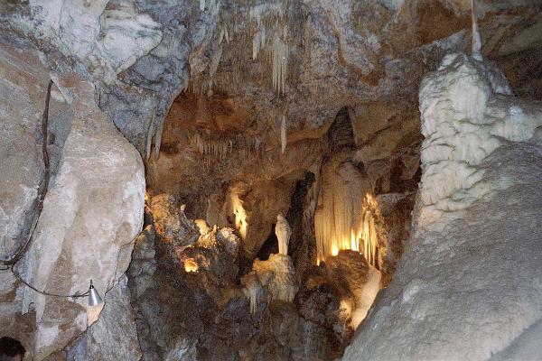 straws and stalactites a cave formation with stalactites and straws hanging from the ceiling, a large flowstone formation on the right