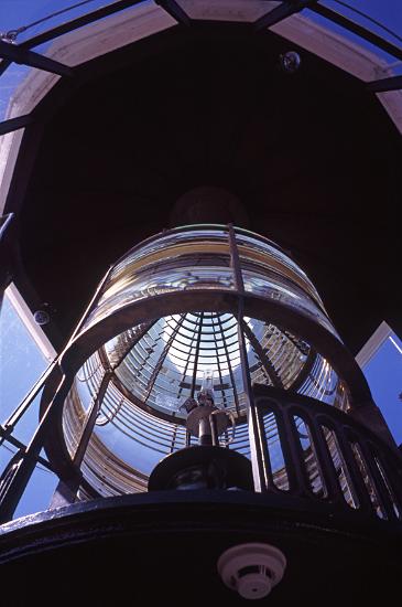 a low angle view of the complex lens and lighting system in a lighthouse lantern room.
